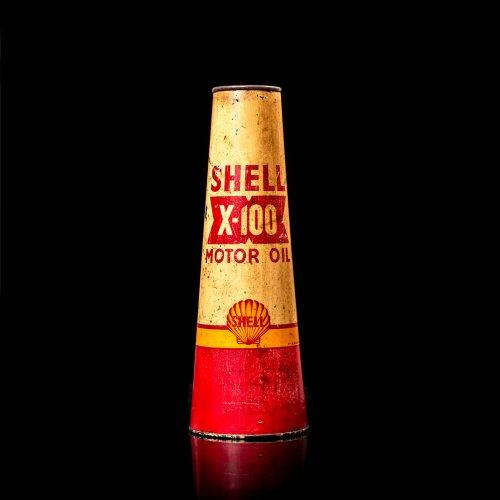 Vintage Shell oil cans with red and yellow branding from the 1900-1920 old logo Vintage Shell oil cans from 1900-19255, featuring the old logo. The photo showcases an antique tin red with yellow accents, displaying the historic Shell emblem. Shot in a studio against a solid black background