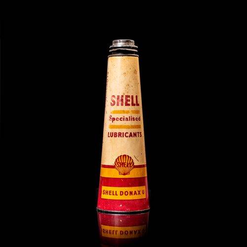 Vintage Shell oil cans with red and yellow branding from the 1900-1920 old logo Vintage Shell oil cans from 1900-19255, featuring the old logo. The photo showcases an antique tin red with yellow accents, displaying the historic Shell emblem. Shot in a studio against a solid black background