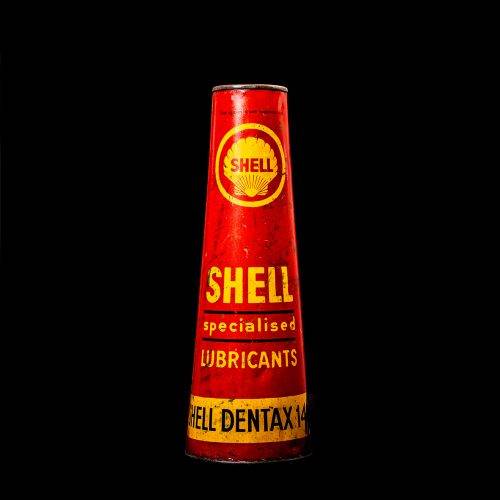 Rare and unique vintage conical shell oil can from 1900–1950 with a red base and yellow accents, featuring the classic shell logo. This antique, cone-shaped motor oil tin is showcased in a studio setting against a solid black background."