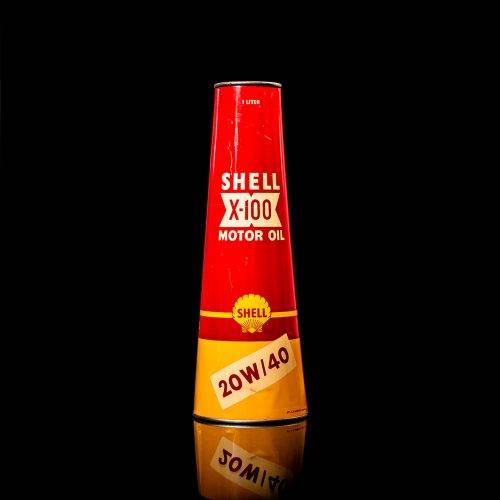 Rare and unique vintage conical shell oil can from 1900–1950 with a red base and yellow accents, featuring the classic shell logo. This antique, cone-shaped motor oil tin is showcased in a studio setting against a solid black background."