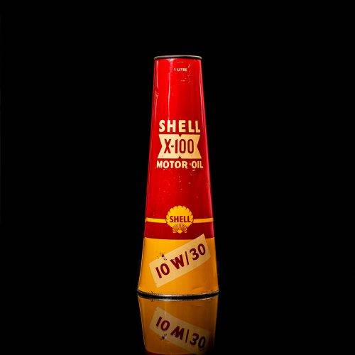 Rare and unique vintage conical shell oil can from 1900–1950 with a red base and yellow accents, featuring the classic shell logo. This antique, cone-shaped motor oil tin is showcased in a studio setting against a solid black background."