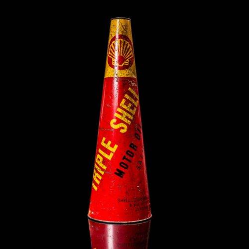 Rare and unique vintage conical shell oil can from 1900–1950 with a red base and yellow accents, featuring the classic shell logo. This antique, cone-shaped motor oil tin is showcased in a studio setting against a solid black background."