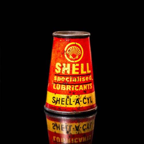 Vintage Shell oil cans with red and yellow branding from the 1900-1920 old logo Vintage Shell oil cans from 1900-19255, featuring the old logo. The photo showcases an antique tin red with yellow accents, displaying the historic Shell emblem. Shot in a studio against a solid black background