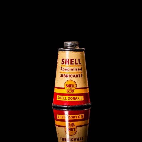 Rare and unique vintage conical shell oil can from 1900–1950 with a red base and yellow accents, featuring the classic shell logo. This antique, cone-shaped motor oil tin is showcased in a studio setting against a solid black background."