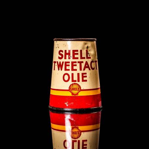 Vintage Shell oil cans with red and yellow branding from the 1900-1920 old logo Vintage Shell oil cans from 1900-19255, featuring the old logo. The photo showcases an antique tin red with yellow accents, displaying the historic Shell emblem. Shot in a studio against a solid black background