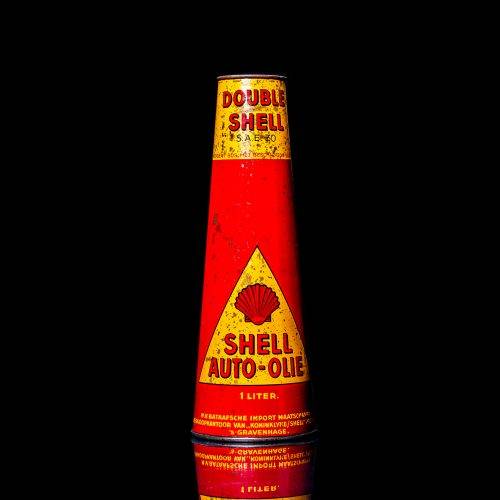 Vintage Shell oil cans with red and yellow branding from the 1900-1920 old logo Vintage Shell oil cans from 1900-19255, featuring the old logo. The photo showcases an antique tin red with yellow accents, displaying the historic Shell emblem. Shot in a studio against a solid black background