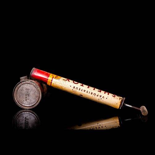Rare and unique vintage Shell flitgun from 1900–1950 with a red base and yellow accents, featuring the classic Shell logo. This antique insect spray canister is displayed in a studio setting against a solid black background