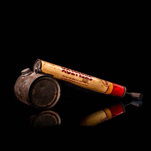 Rare and unique vintage Shell flitgun from 1900–1950 with a red base and yellow accents, featuring the classic Shell logo. This antique insect spray canister is displayed in a studio setting against a solid black background
