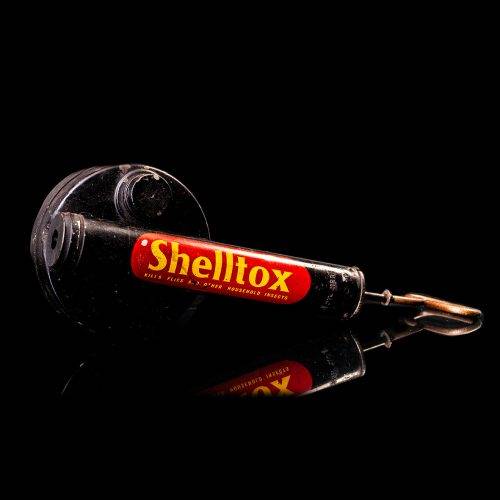 Rare and unique vintage Shell flitgun from 1900–1950 with a red base and yellow accents, featuring the classic Shell logo. This antique insect spray canister is displayed in a studio setting against a solid black background