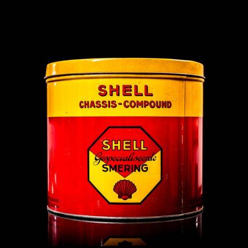 Vintage Shell oil cans with red and yellow branding from the 1900-1920 old logo Vintage Shell oil cans from 1900-19255, featuring the old logo. The photo showcases an antique tin red with yellow accents, displaying the historic Shell emblem. Shot in a studio against a solid black background