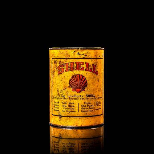 Rare and unique vintage Shell grease can from 1900–1950 with a red base and yellow detailing, featuring the classic Shell logo. This antique lubricant tin is displayed in a studio setting against a solid black background.