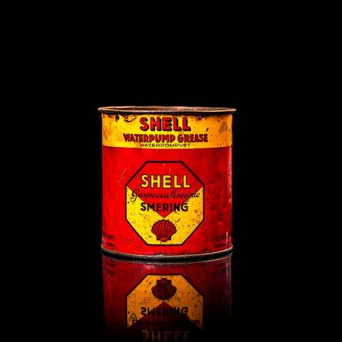 Rare and unique vintage Shell grease can from 1900–1950 with a red base and yellow detailing, featuring the classic Shell logo. This antique lubricant tin is displayed in a studio setting against a solid black background.