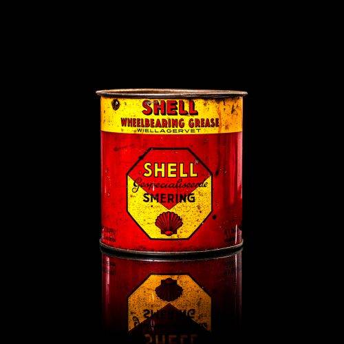Vintage Shell oil cans with red and yellow branding from the 1900-1920 old logo Vintage Shell oil cans from 1900-19255, featuring the old logo. The photo showcases an antique tin red with yellow accents, displaying the historic Shell emblem. Shot in a studio against a solid black background