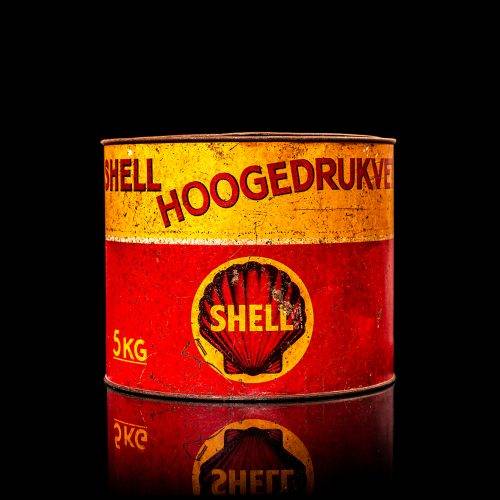 Rare and unique vintage Shell grease can from 1900–1950 with a red base and yellow detailing, featuring the classic Shell logo. This antique lubricant tin is displayed in a studio setting against a solid black background.