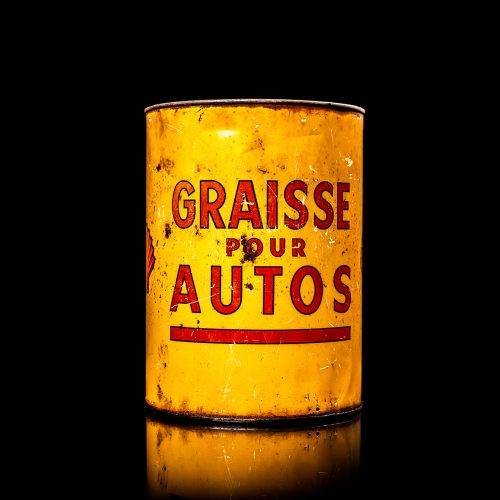 Rare and unique vintage Shell grease can from 1900–1950 with a red base and yellow detailing, featuring the classic Shell logo. This antique lubricant tin is displayed in a studio setting against a solid black background.