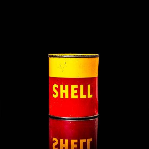 Rare and unique vintage Shell grease can from 1900–1950 with a red base and yellow detailing, featuring the classic Shell logo. This antique lubricant tin is displayed in a studio setting against a solid black background."