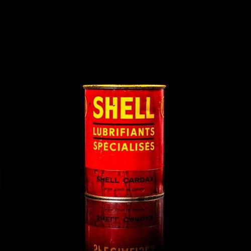 Vintage Shell oil cans with red and yellow branding from the 1900-1920 old logo Vintage Shell oil cans from 1900-19255, featuring the old logo. The photo showcases an antique tin red with yellow accents, displaying the historic Shell emblem. Shot in a studio against a solid black background