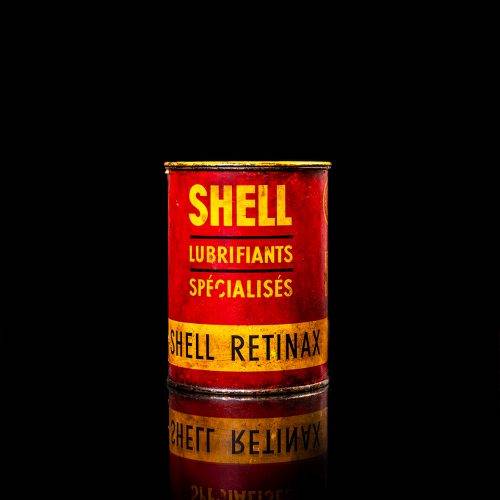 Rare and unique vintage Shell grease can from 1900–1950 with a red base and yellow detailing, featuring the classic Shell logo. This antique lubricant tin is displayed in a studio setting against a solid black background."