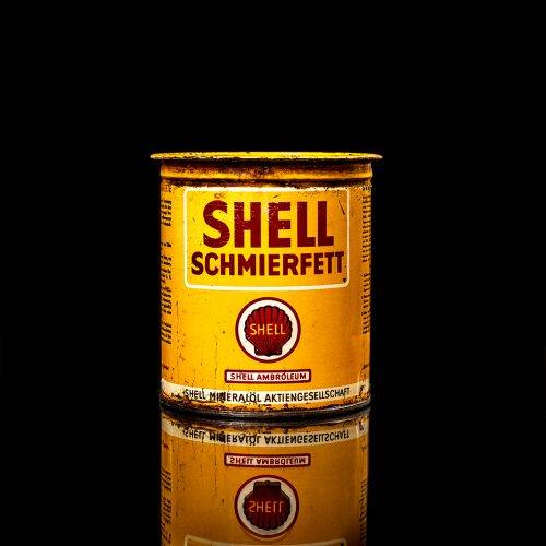 Vintage Shell oil cans with red and yellow branding from the 1900-1920 old logo Vintage Shell oil cans from 1900-19255, featuring the old logo. The photo showcases an antique tin red with yellow accents, displaying the historic Shell emblem. Shot in a studio against a solid black background