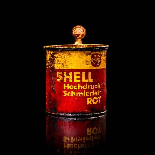 Vintage Shell oil cans with red and yellow branding from the 1900-1920 old logo Vintage Shell oil cans from 1900-19255, featuring the old logo. The photo showcases an antique tin red with yellow accents, displaying the historic Shell emblem. Shot in a studio against a solid black background