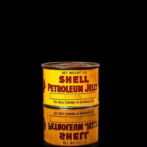 Vintage Shell oil cans with red and yellow branding from the 1900-1920 old logo Vintage Shell oil cans from 1900-19255, featuring the old logo. The photo showcases an antique tin red with yellow accents, displaying the historic Shell emblem. Shot in a studio against a solid black background