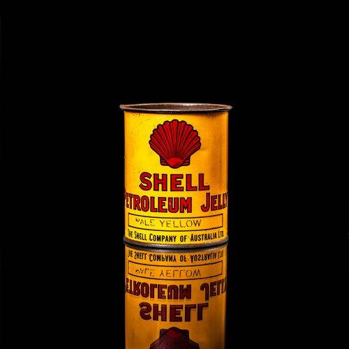 Vintage Shell oil cans with red and yellow branding from the 1900-1920 old logo Vintage Shell oil cans from 1900-19255, featuring the old logo. The photo showcases an antique tin red with yellow accents, displaying the historic Shell emblem. Shot in a studio against a solid black background