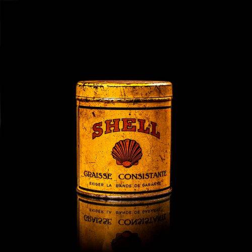 Vintage Shell oil cans with red and yellow branding from the 1900-1920 old logo Vintage Shell oil cans from 1900-19255, featuring the old logo. The photo showcases an antique tin red with yellow accents, displaying the historic Shell emblem. Shot in a studio against a solid black background