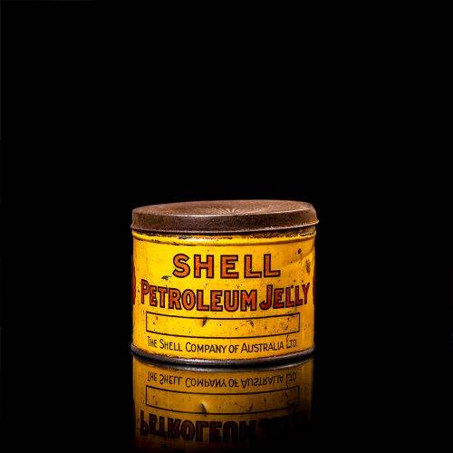 Rare and unique vintage Shell grease can from 1900–1950 with a red base and yellow detailing, featuring the classic Shell logo. This antique lubricant tin is displayed in a studio setting against a solid black background."