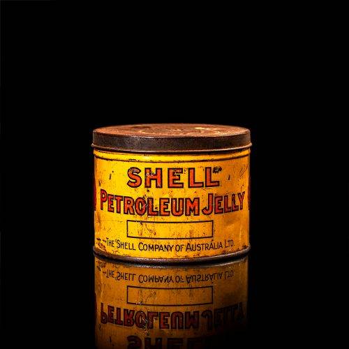 Vintage Shell oil cans with red and yellow branding from the 1900-1920 old logo Vintage Shell oil cans from 1900-19255, featuring the old logo. The photo showcases an antique tin red with yellow accents, displaying the historic Shell emblem. Shot in a studio against a solid black background