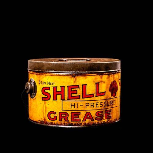 Vintage Shell oil cans with red and yellow branding from the 1900-1920 old logo Vintage Shell oil cans from 1900-19255, featuring the old logo. The photo showcases an antique tin red with yellow accents, displaying the historic Shell emblem. Shot in a studio against a solid black background