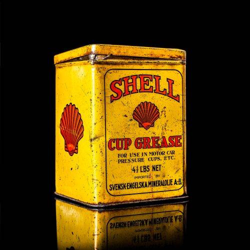 Vintage Shell oil cans with red and yellow branding from the 1900-1920 old logo Vintage Shell oil cans from 1900-19255, featuring the old logo. The photo showcases an antique tin red with yellow accents, displaying the historic Shell emblem. Shot in a studio against a solid black background