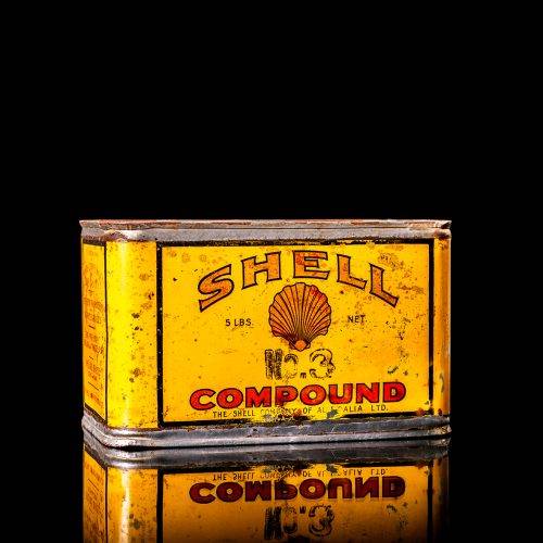 Rare and unique vintage Shell grease can from 1900–1950 with a red base and yellow detailing, featuring the classic Shell logo. This antique lubricant tin is displayed in a studio setting against a solid black background."