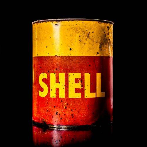 Rare and unique vintage Shell grease can from 1900–1950 with a red base and yellow detailing, featuring the classic Shell logo. This antique lubricant tin is displayed in a studio setting against a solid black background."