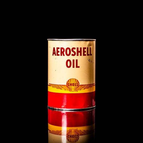 Rare and unique vintage Shell grease can from 1900–1950 with a red base and yellow detailing, featuring the classic Shell logo. This antique lubricant tin is displayed in a studio setting against a solid black background."