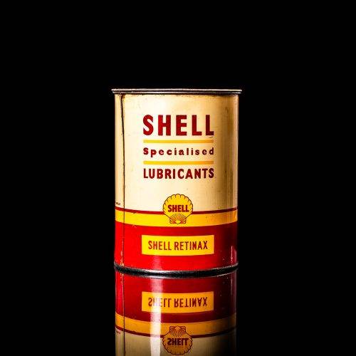 Vintage Shell oil cans with red and yellow branding from the 1900-1920 old logo Vintage Shell oil cans from 1900-19255, featuring the old logo. The photo showcases an antique tin red with yellow accents, displaying the historic Shell emblem. Shot in a studio against a solid black background