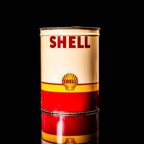 Rare and unique vintage Shell grease can from 1900–1950 with a red base and yellow detailing, featuring the classic Shell logo. This antique lubricant tin is displayed in a studio setting against a solid black background."
