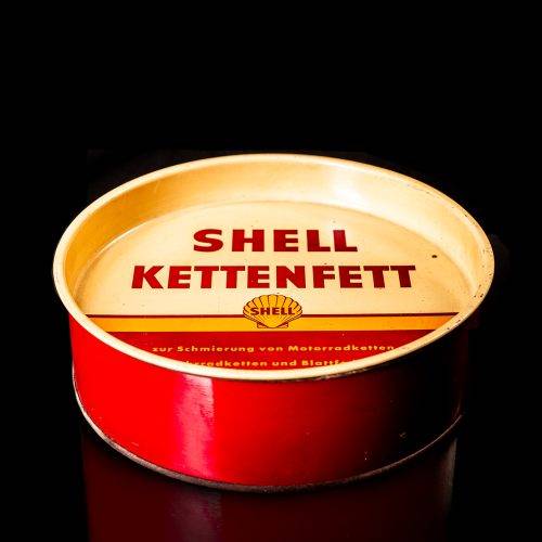 Rare and unique vintage Shell grease can from 1900–1950 with a red base and yellow detailing, featuring the classic Shell logo. This antique lubricant tin is displayed in a studio setting against a solid black background."