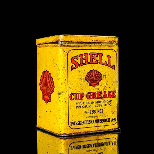Vintage Shell oil cans with red and yellow branding from the 1900-1920 old logo Vintage Shell oil cans from 1900-19255, featuring the old logo. The photo showcases an antique tin red with yellow accents, displaying the historic Shell emblem. Shot in a studio against a solid black background