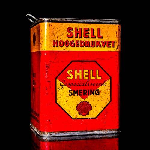 Rare and unique vintage Shell grease can from 1900–1950 with a red base and yellow detailing, featuring the classic Shell logo. This antique lubricant tin is displayed in a studio setting against a solid black background."