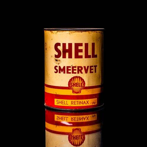 Rare and unique vintage Shell grease can from 1900–1950 with a red base and yellow detailing, featuring the classic Shell logo. This antique lubricant tin is displayed in a studio setting against a solid black background."