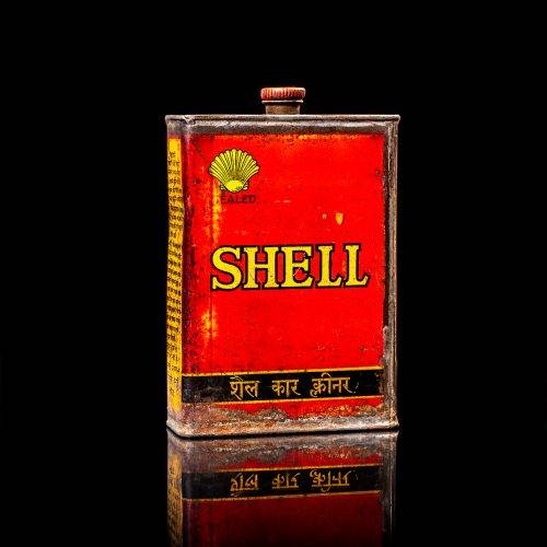 Rare and unique vintage mini Shell oil can from 1900–1950 with red and yellow accents, featuring the classic Shell logo. This small antique tin is displayed in a studio setting against a solid black background. lubricant,cleaner, outboard, motor oil, sealant, valve lubricant, two cycle, glass cleaner oil, shell cans