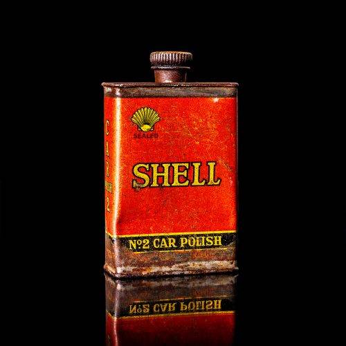 Rare and unique vintage mini Shell oil can from 1900–1950 with red and yellow accents, featuring the classic Shell logo. This small antique tin is displayed in a studio setting against a solid black background. lubricant,cleaner, outboard, motor oil, sealant, valve lubricant, two cycle, glass cleaner oil, shell cans
