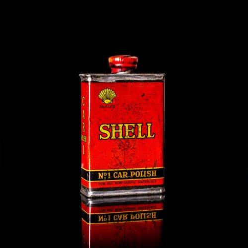 Vintage Shell oil cans with red and yellow branding from the 1900-1920 old logo Vintage Shell oil cans from 1900-19255, featuring the old logo. The photo showcases an antique tin red with yellow accents, displaying the historic Shell emblem. Shot in a studio against a solid black background