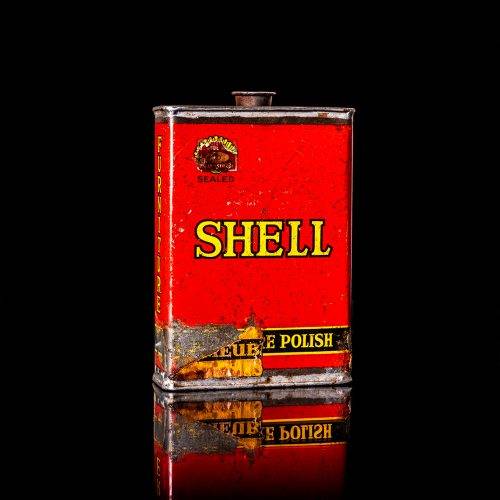 Rare and unique vintage mini Shell oil can from 1900–1950 with red and yellow accents, featuring the classic Shell logo. This small antique tin is displayed in a studio setting against a solid black background. lubricant,cleaner, outboard, motor oil, sealant, valve lubricant, two cycle, glass cleaner oil, shell cans