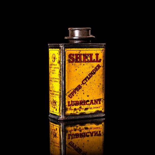 Vintage Shell oil cans with red and yellow branding from the 1900-1920 old logo Vintage Shell oil cans from 1900-19255, featuring the old logo. The photo showcases an antique tin red with yellow accents, displaying the historic Shell emblem. Shot in a studio against a solid black background
