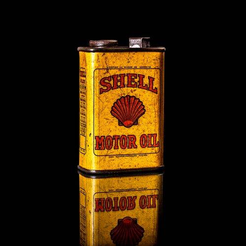 Vintage Shell oil cans with red and yellow branding from the 1900-1920 old logo Vintage Shell oil cans from 1900-19255, featuring the old logo. The photo showcases an antique tin red with yellow accents, displaying the historic Shell emblem. Shot in a studio against a solid black background