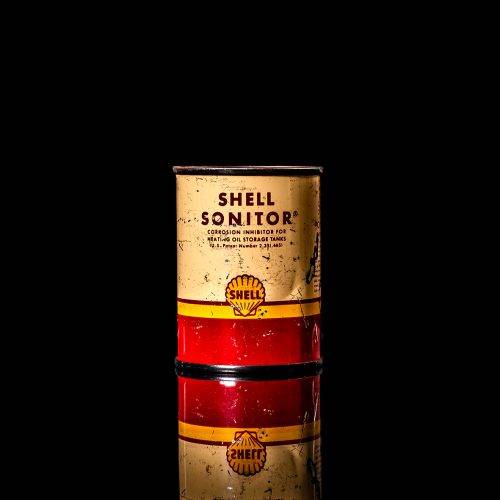 Vintage Shell oil cans with red and yellow branding from the 1900-1920 old logo Vintage Shell oil cans from 1900-19255, featuring the old logo. The photo showcases an antique tin red with yellow accents, displaying the historic Shell emblem. Shot in a studio against a solid black background