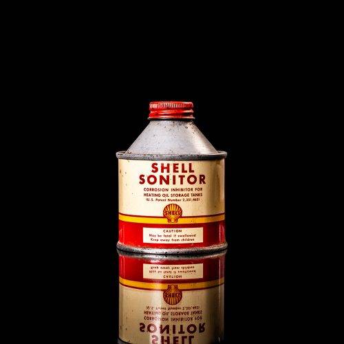 Vintage Shell oil cans with red and yellow branding from the 1900-1920 old logo Vintage Shell oil cans from 1900-19255, featuring the old logo. The photo showcases an antique tin red with yellow accents, displaying the historic Shell emblem. Shot in a studio against a solid black background