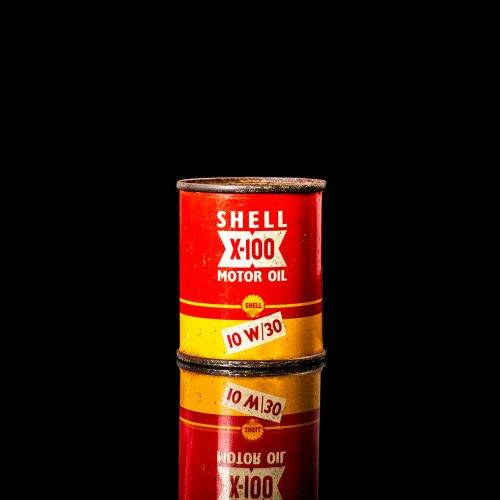 Vintage Shell oil cans with red and yellow branding from the 1900-1920 old logo Vintage Shell oil cans from 1900-19255, featuring the old logo. The photo showcases an antique tin red with yellow accents, displaying the historic Shell emblem. Shot in a studio against a solid black background