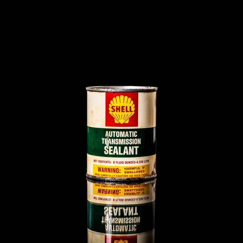 Vintage Shell oil cans with red and yellow branding from the 1900-1920 old logo Vintage Shell oil cans from 1900-19255, featuring the old logo. The photo showcases an antique tin red with yellow accents, displaying the historic Shell emblem. Shot in a studio against a solid black background